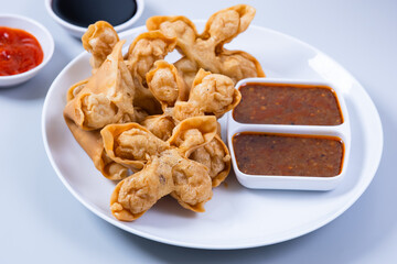 Batagor,(Fried Tofu Meatballs), served on a serving plate with peanut sauce, sambal, and chili sauce. This is authentic street food from Bandung Indonesia. Perfect for recipes, articles or any cooking