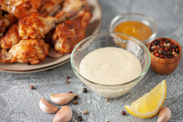 Alabama white BBQ sauce in bowl and ingredient for dip on grey background.
