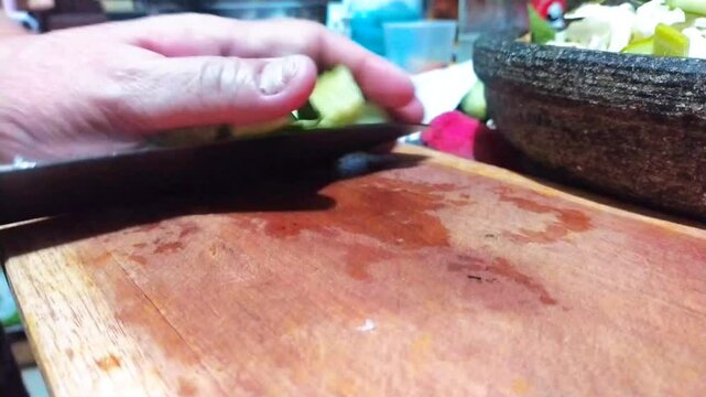 cutting cucumber on a cutting board as one of Lotek's cooking ingredients. Lotek is a salad made from Javanese (Indonesian) vegetables with peanut sauce
