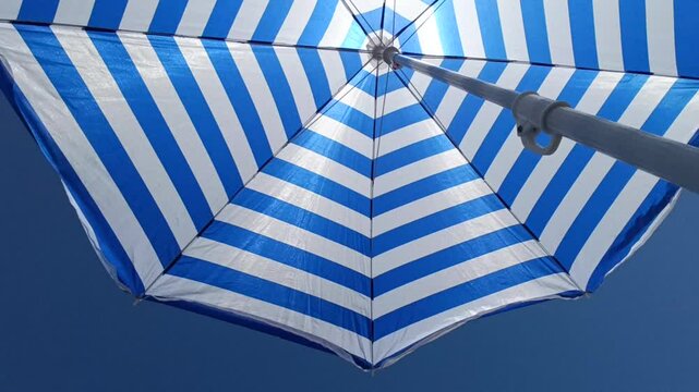 striped beach umbrella on a blue sky background