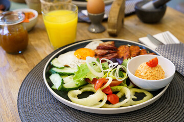 Breakfast with bacon, fried eggs, sausage and salad