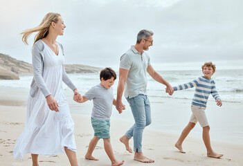 Parents, kids and holding hands at beach with smile, walk or bonding with love on vacation in summer. Father, mother and children on holiday for connection, memory or talking with family in sunshine