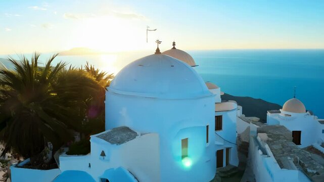 Sun-drenched Santorini cliffside adorned with iconic white buildings and blue domes. Palm tree frames picturesque scene. Azure sea and clear sky create stunning backdrop for Greek island beauty.	