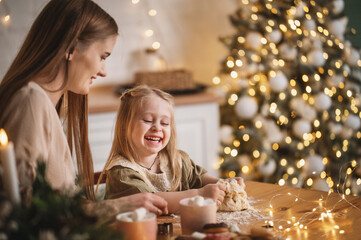 pregnant woman and her 3 year old daughter near the New Year tree in kitchen cooking. Noise blurred toned vintage film grain image	