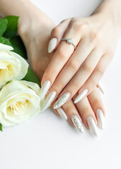 Female Hands on a white background with beautiful pearl manicure and white roses.