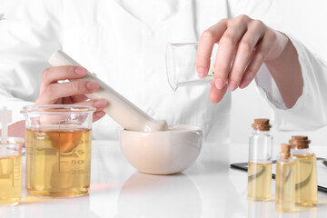 Aromatherapy product. Scientist developing essential oils at white table in laboratory, closeup
