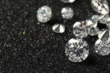 Beautiful dazzling diamonds on dark shiny background, closeup. Space for text