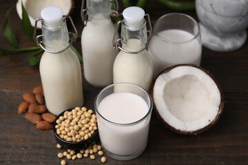 Different types of vegan milk and ingredients on wooden table