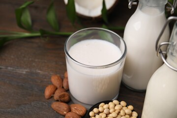 Different types of vegan milk and ingredients on wooden table, closeup