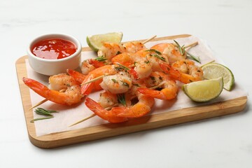 Skewers with delicious grilled shrimps served on white table