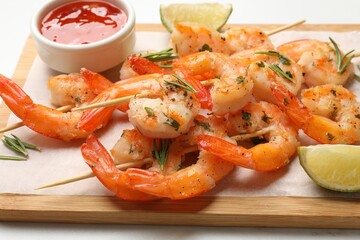 Skewers with delicious grilled shrimps served on white table, closeup