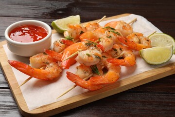 Skewers with delicious grilled shrimps served on wooden table, closeup