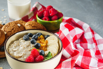tasty nutritious oatmeal with fruits and berries on a light stone background