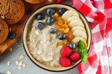 tasty nutritious oatmeal with fruits and berries on a light stone background