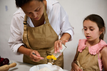 Mother and daughter baking together in the kitchen, preparing ingredients