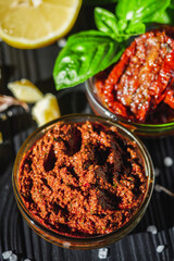 fresh pesto sauce with sun-dried tomatoes on a black wooden rustic background