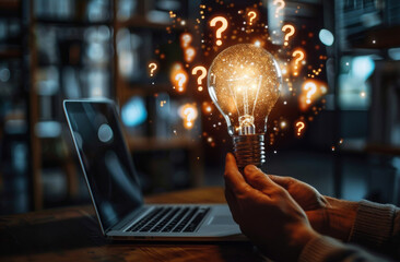 Light bulb with floating question marks near a laptop symbolizing ideas and innovation