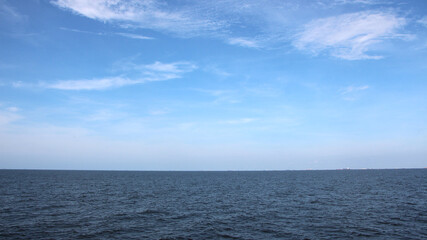 Obraz premium The expanse of sea stretches under a blue sky with white clouds