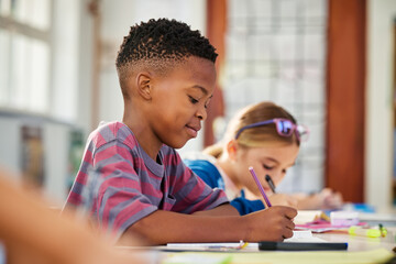 Little african boy writing in classroom during test