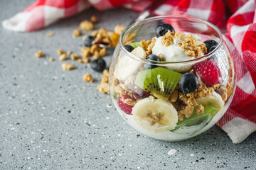 delicious crunchy granola dessert with berries and fruits on a gray stone background