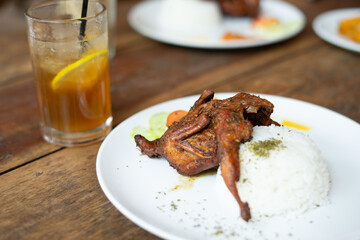 Fried quail served with spicy sambal and rice, showcasing a delicious traditional meal, perfect for food, culture, and culinary