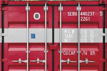 Latvia flag depicted on metal doors of shipping cargo container outdoors in docks area close up