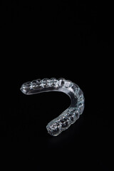 A clear mouth guard resting on a black surface under the light