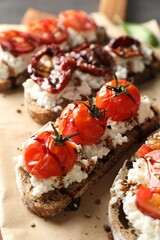 Delicious ricotta bruschettas with sun dried tomatoes and sauce on parchment, closeup