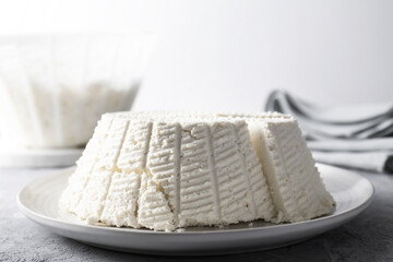 Tasty ricotta (cream cheese) on grey textured table, closeup