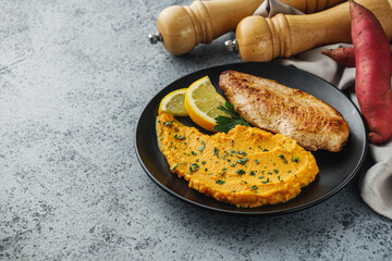 delicious mashed sweet potatoes and fried chicken breast on a light stone background