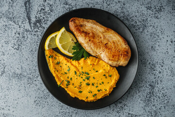 delicious mashed sweet potatoes and fried chicken breast on a light stone background