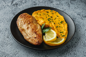 delicious mashed sweet potatoes and fried chicken breast on a light stone background