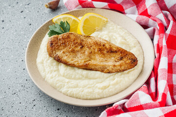 delicious mashed cauliflower and fried chicken breast on a light stone background