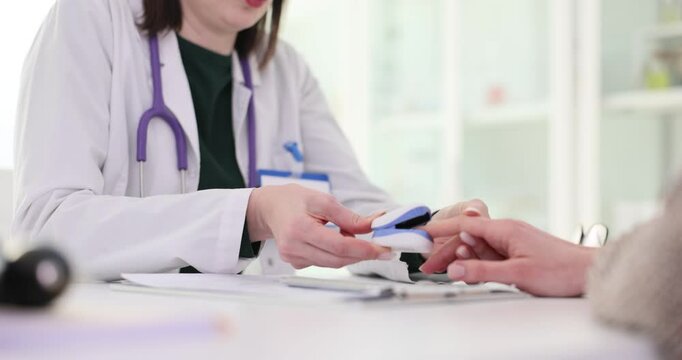 Doctor places pulse oximeter on woman finger at appointment