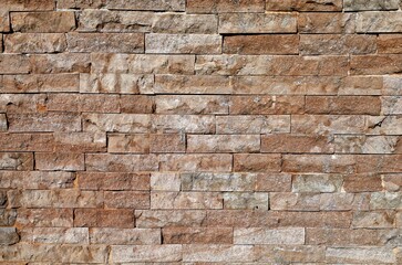 Old external stone wall made of brown limestone bricks. Background and texture. Full frame.