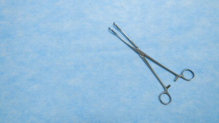 Fototapeta premium Sponge holding forceps are used during surgical procedures to hold sponges and swabs. Medical Equipment used by surgeons in surgery placed on a blue background.