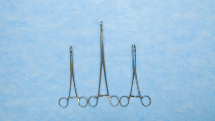 Fototapeta premium Sponge holding forceps are used during surgical procedures to hold sponges and swabs. Medical Equipment used by surgeons in surgery placed on a blue background.