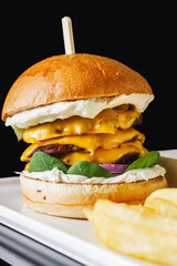 a delicious cheeseburger with three beef cutlets and a cheese bath