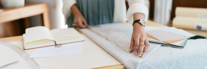 Fashion seamstress woman use tape measure to measuring textile garment pattern for fashion clothes..