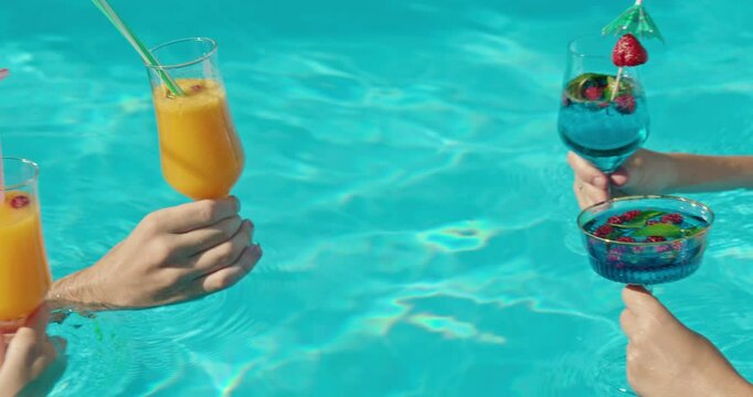 Group of people clinking beautiful glasses with refreshing drinks against the pool water surface