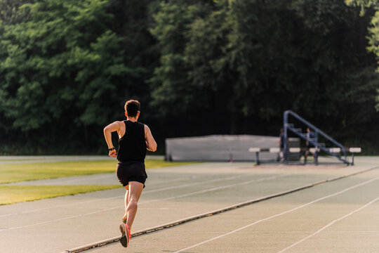 Athlete running on the inside lane of the athletics track during a race - Powered by Adobe