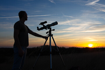 Amateur astronomer observing Solar eclipse and Sun with a telescope and special solar filter.