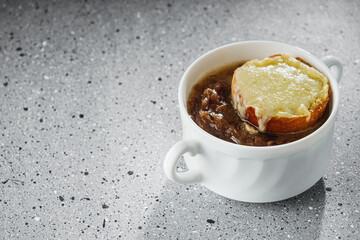 delicious original French onion soup on a light stone background