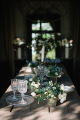 Beautiful summer dinner table setting outdoors, with vintage plates, candles, wine glasses and jasmine and forget me not flowers on the wooden table 