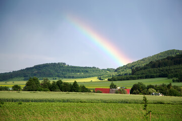 Tęcza nad górami, zielone pola, dachy domów. © Stanisław Błachowicz