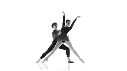 Ballet partners perfecting their form during practice session against white studio background. Black and white filter. Concept of pair training, classic ballet, inspiration, beauty, creativity. Ad.