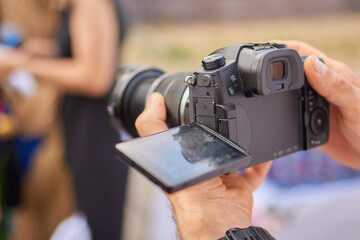 Closeup image showing someone gripping a DSLR camera with an articulated screen