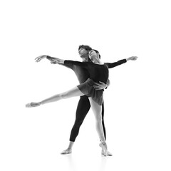 Grace and elegance. Young ballet dancers training in motion against white studio background. Monochrome filter. Concept of pair training, classic ballet, inspiration, beauty, creativity. Ad.
