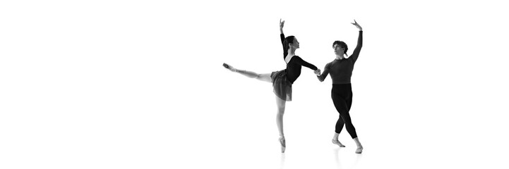 Young ballet dancers, man and woman demonstrate synchronized elegance during training against white...