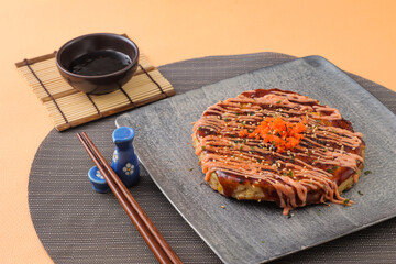 Mentaiko Octopus Okonomiyaki with chopsticks served in dish isolated on background side view of japanese food